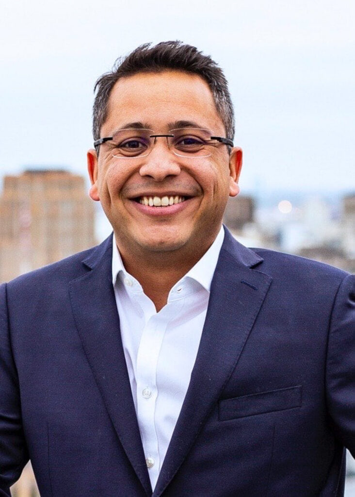 Man with glasses smiles into the camera