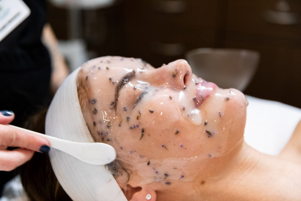 Side shot of woman lying down as professional covers her face with mask.