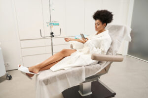 A woman on her phone in a bathrobe receives an IV drip infusion in Morris County, NJ.