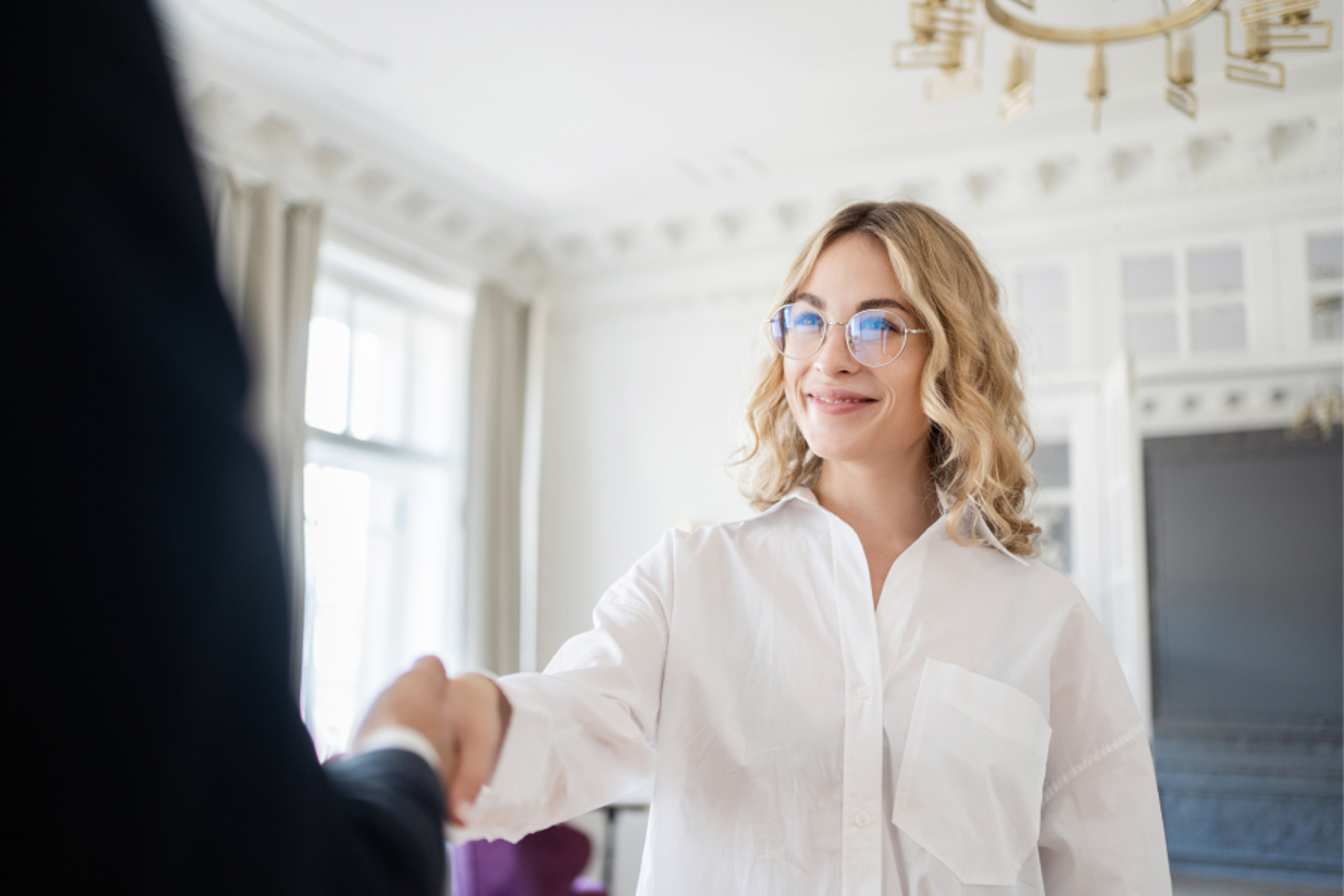 A young blonde woman shaking hands with her provider at the ends of her consultation at Exhibit Medical Aesthetics, a trusted med spa near Madison, NJ.