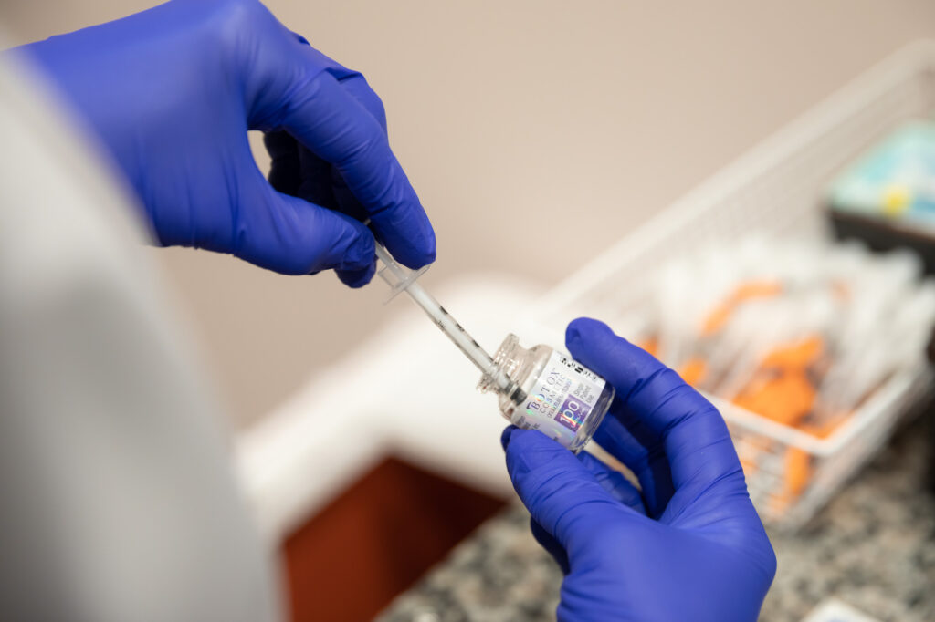 Gloved hands holding bottle of Dysport and syringe.