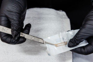 Gloved hands holding dermaplaner for menopause skin care in Denville.