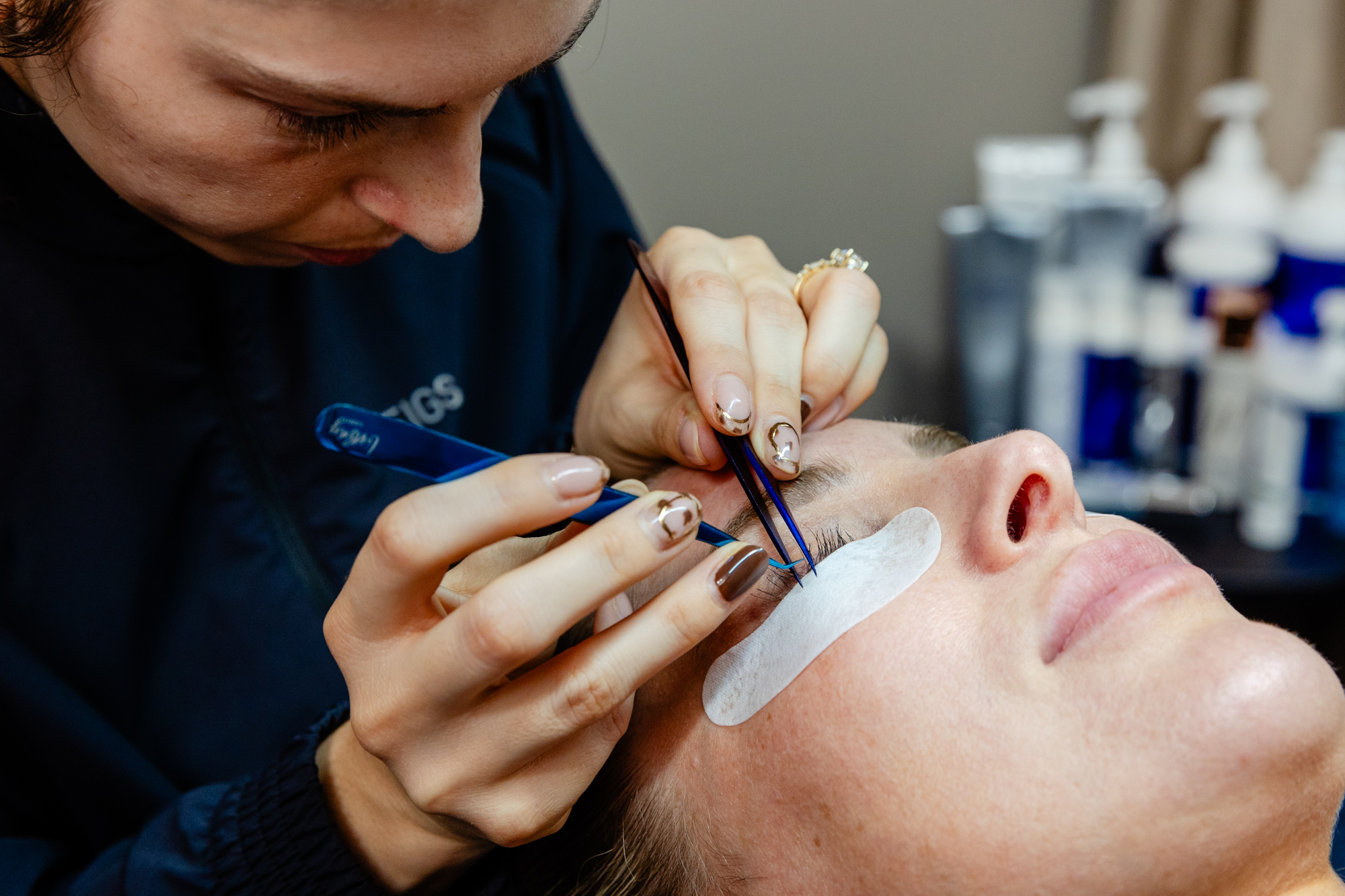 Nurse applies lash extensions holding tweezers