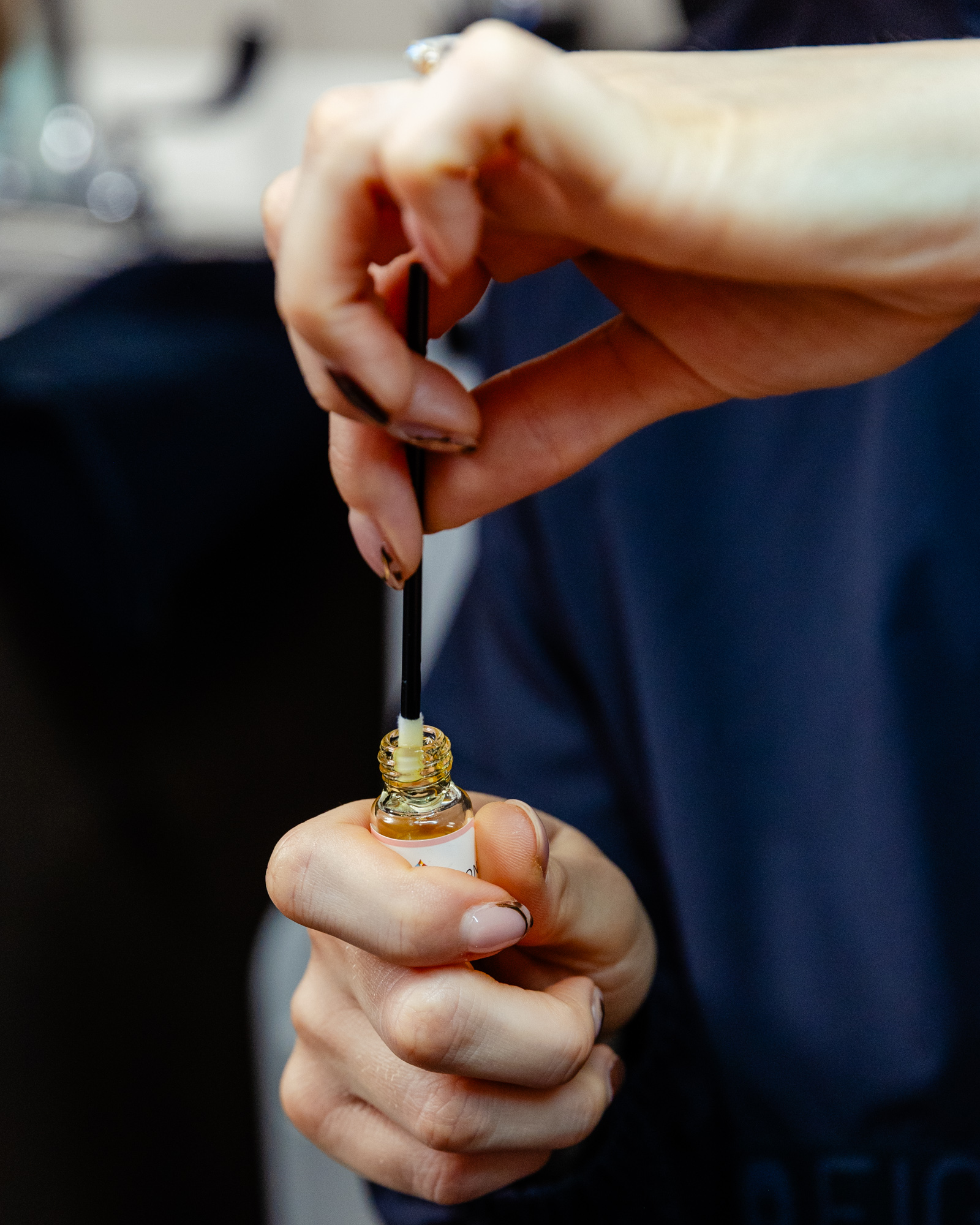 Person holding small bottle and stick