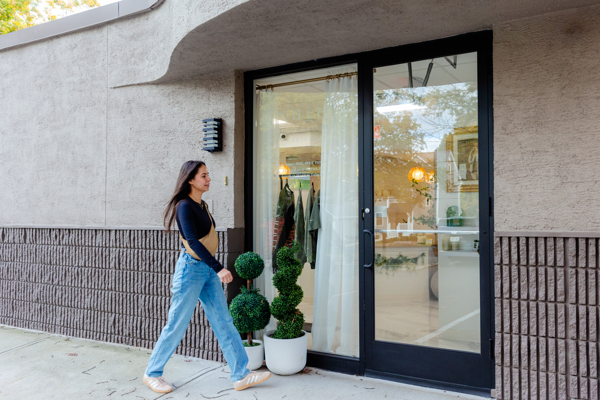 A young woman walking to the front door of Exhibit Medical Aesthetics, getting ready to go in to receive her treatment if Skinvive near Chatham, NJ.