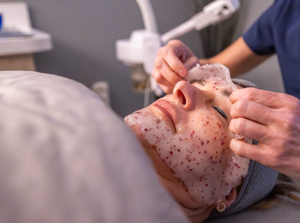 Woman lying down as professional removes facial mask.