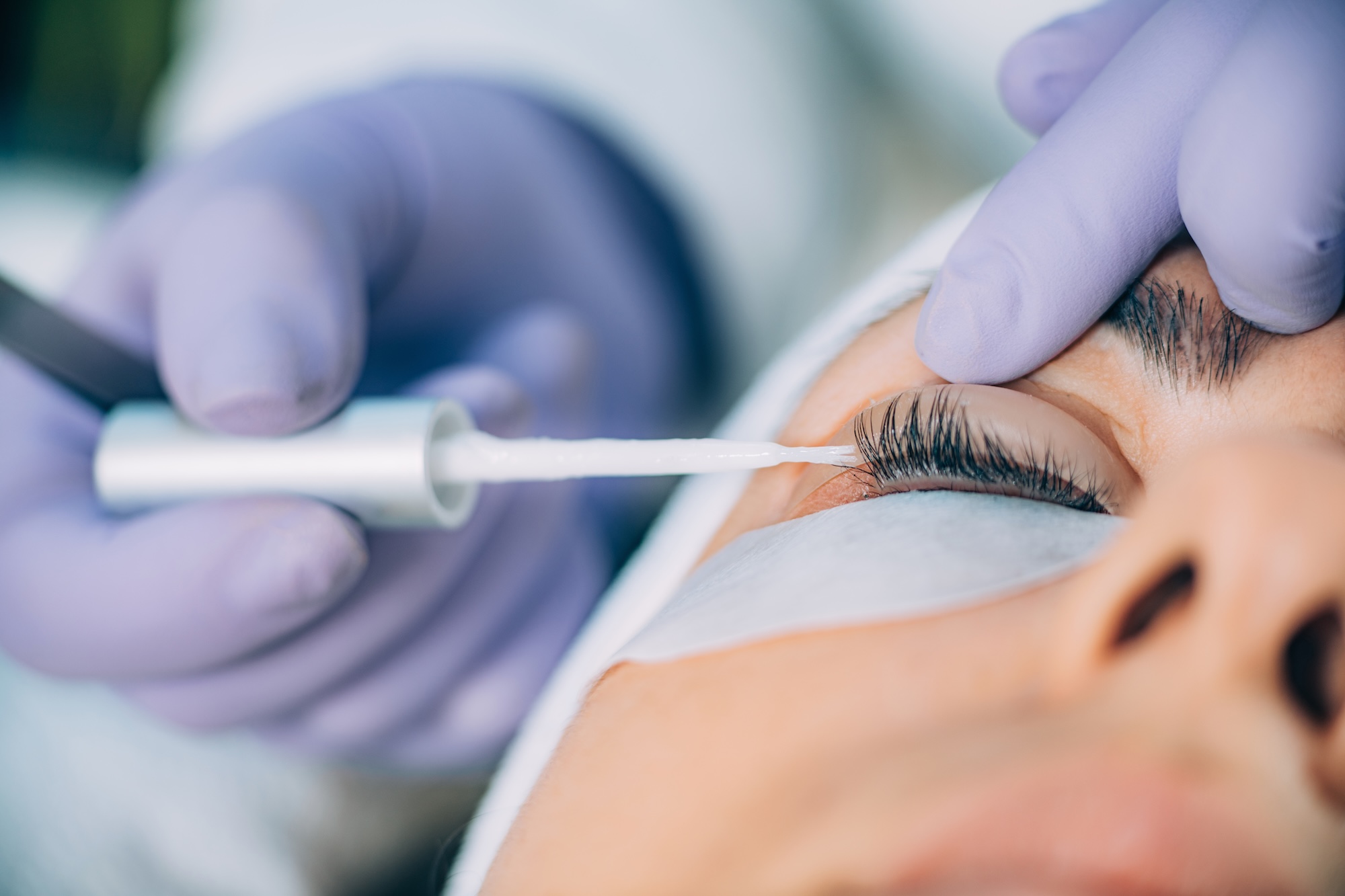 An aesthetician at Exhibit Medical Aesthetics spreading out a female patient's eyelashes before providing a lash lift near Chatham, NJ.